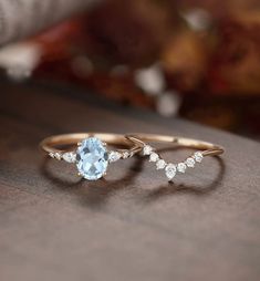 two gold rings with an aqua blue topazte and white diamonds on a table