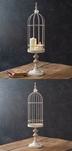 a white birdcage sitting on top of a wooden table next to a candle