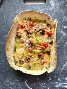 a tortilla with black olives, tomatoes and other toppings on it