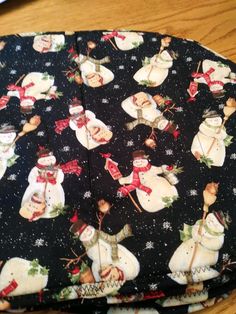 three snowmen on black fabric with red and white bows are sitting next to each other