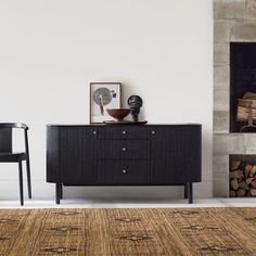 a black cabinet sitting next to a fireplace in a living room on top of a rug