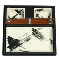 two chopsticks and one plate with black ink on it in a box,