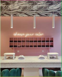 the interior of a nail salon with pink walls and white counter tops, green chairs, and neon lights