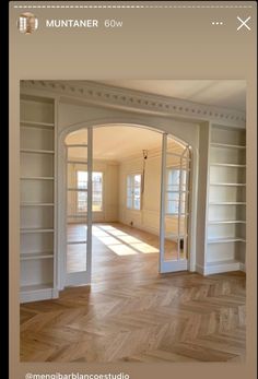 an empty room with white bookcases and wood flooring is seen on the phone