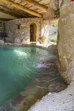 an indoor swimming pool surrounded by rocks and water features a stone walkway leading to the door