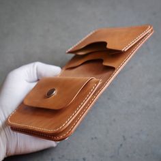 a hand holding an empty wallet in it's left side, with the card slot partially open