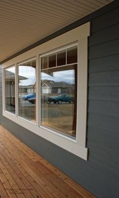 an empty porch with wood flooring and white trim on the side of a house