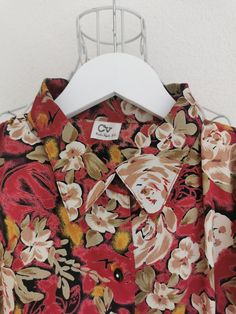 Vintage floral print polyester blouse from the 1980's. Women's button down floral print blouse in red, green, beige and yellow colors. Has elastic bottom hem and a pleated detail on the shoulders (with shoulder pads). Oversized fit. Material: 100% Polyester Size: 44 DE which is 14 US or XL. Model on the picture is 40 DE. To be sure this item would fit you, please look at the measurements below. Measurements (taken while blouse is lying flat, double waist): Shoulder to Shoulder (from seam to seam Red Retro Print Shirt For Spring, Vintage Red Shirt For Spring, Red Vintage Print Shirt, Retro Collared Blouse With Floral Print, Vintage Collared Top With Floral Print, Red Vintage Shirt With Vintage Print, Vintage Printed Collared Blouse, Red Collared Printed Blouse, Vintage Red Shirt With Floral Print