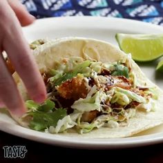 a person is holding a tortilla with chicken and lettuce on it