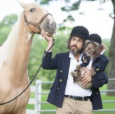 a man holding a small dog while standing next to a horse