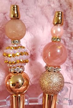 three different types of perfume bottles with gold and pink decorations on them next to a white furnishing