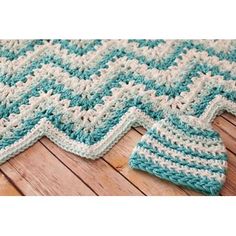 a blue and white crocheted blanket sitting on top of a wooden floor