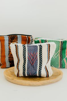 three colorful striped bags sitting on top of a wooden tray