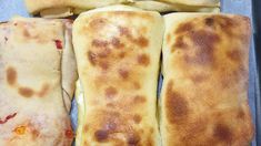 four pieces of flat bread sitting on top of a baking pan covered in melted cheese