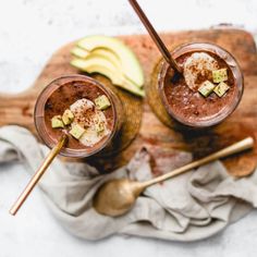 two glasses filled with chocolate pudding and topped with avocado