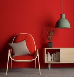 a red chair sitting next to a book shelf on top of a carpeted floor