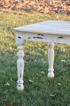 an old white table sitting in the grass