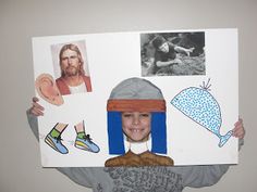 a child holding up a paper cutout with pictures on it's face and wearing a hat