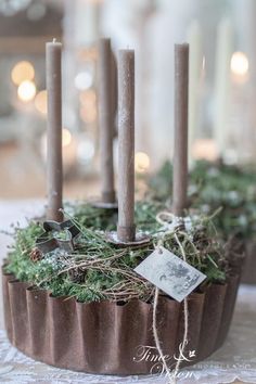 some candles are sitting in a cupcake with moss and ivy around them on a table