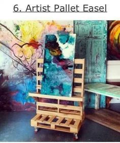 a chair made out of pallets in front of paintings