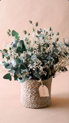 a basket filled with white flowers and greenery