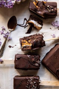 several pieces of chocolate cake sitting on top of a white plate with purple flowers and spoons