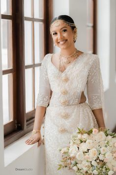 a woman standing next to a window holding a bouquet