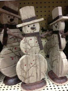 two snowmen made out of wood sitting next to each other on top of a shelf