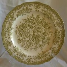 a green and white plate sitting on top of a cloth covered tablecloth with an ornate design