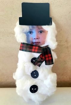 a snowman with a hat and scarf on it's head is shown in front of a wall