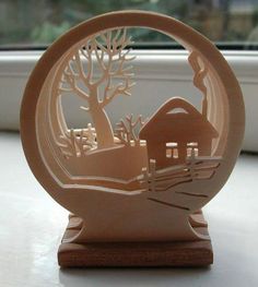 a wooden carving of a house and tree in the middle of a window sill