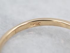 a yellow gold wedding ring with the word love engraved on it's side, sitting on a white surface