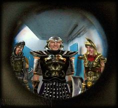 two men dressed in armor are seen through a magnifier lens as another man looks on