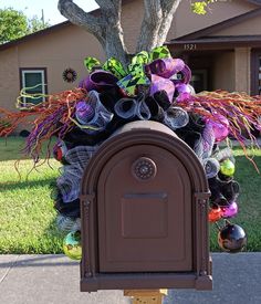 a mailbox decorated with purple and green decorations in front of a house on a sunny day