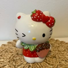 a hello kitty figurine holding a donut on top of a wicker mat