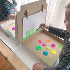 a little boy that is standing in front of a box with magnets on it