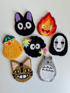 six handmade crocheted animal magnets with faces on them, all decorated in different colors