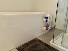 a bathroom with a bathtub, shower and toiletries on the shelf next to it