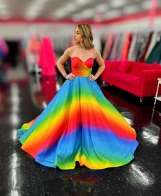 a woman wearing a rainbow colored dress standing in a room