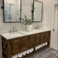 a bathroom with two sinks and mirrors on the wall next to a rug in front of it