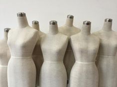 five mannequins are lined up in front of each other, all white