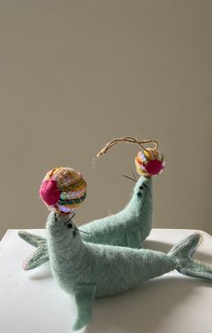 two stuffed animals sitting on top of a white table next to each other and one has a hat on it's head