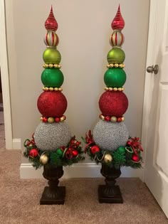 two christmas decorations sitting on top of each other in front of a white door way