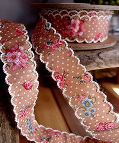 two pieces of fabric with flowers and polka dots on them sitting on a wooden table