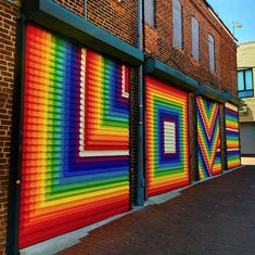 a rainbow painted garage door on the side of a building with brick buildings in the background