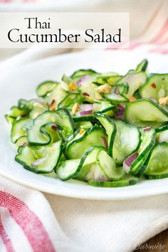 a white plate topped with cucumber salad on top of a table