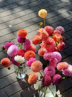 several vases filled with different colored flowers on a brick flooring area next to each other