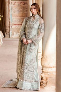 a woman in a long dress standing near columns