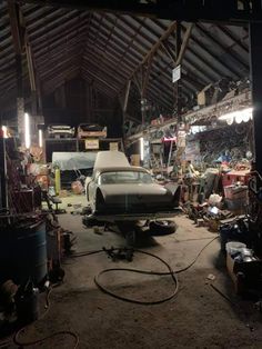 an old car is being worked on in a garage with lots of junk around it