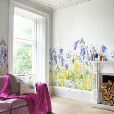 a living room with flowers painted on the wall and a blue couch in front of a fire place